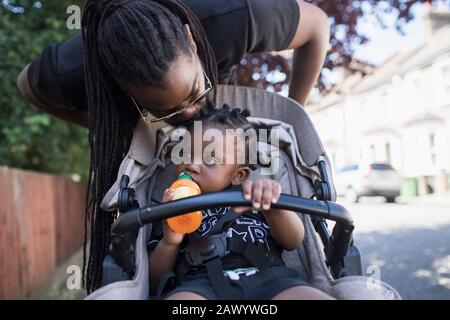 Affectionate father kissing toddler son in stroller Stock Photo
