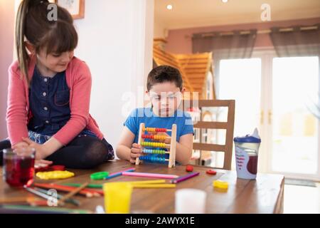 Focused with with Down Syndrome playing with toy at table Stock Photo