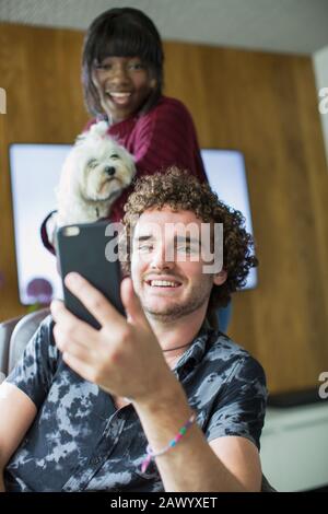Happy young couple with dog video chatting with smart phone Stock Photo