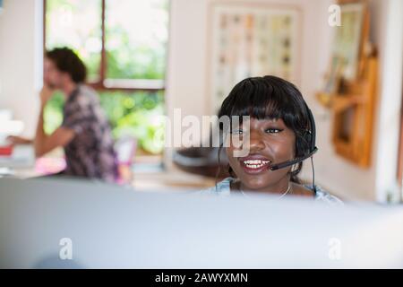 Young woman with headset working from home at computer Stock Photo