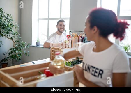 Young man, girl packing up donation boxes looking at each other. Stock Photo