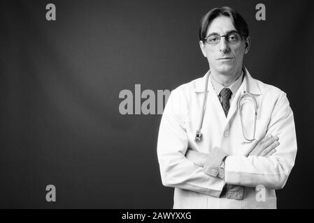 Mature handsome Italian man doctor against gray background Stock Photo