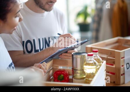 Two volunteers packing a box of charity food. Stock Photo