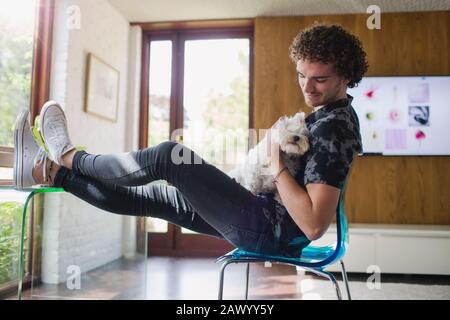 Young man petting dog in home office Stock Photo