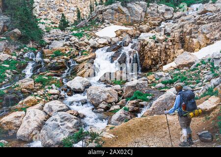 High angle shot of a hiker admiring the small brook on the stones Stock Photo
