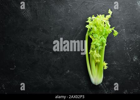 Fresh green celery stalk on a black background. Healthy food. Top view. Free space for your text. Stock Photo