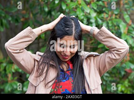 Young Iranian woman in her twenties, smiling and arranging her hair Stock Photo