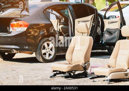 Cream-colored car seats removed from the black car for sun exposure and