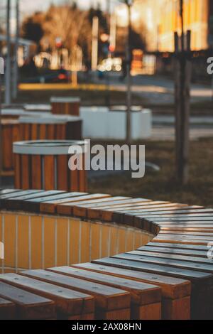 Vertical shot of a circular wooden bench surrounded by trash cans in a park