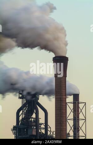Air pollution of a factory with several chimneys in the evening Stock Photo