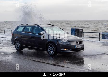 Southend on Sea, Essex, UK. 10th Feb, 2020. The tail end of storm Ciara combined with a high tide has breached the sea defences along the town's Western Esplanade causing a road closure after some traffic braved the water. Volkswagen car with crashing wave Stock Photo