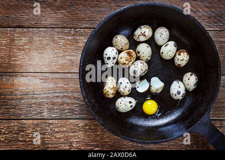 quail eggs in a cast-iron pan on an old wooden table, retro style Stock Photo