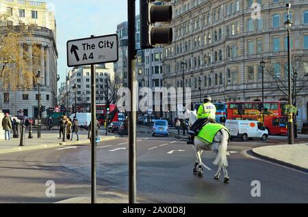 London, United Kingdom - January 19th 2016: Unidentified people and female mounted police officer midst traffic around Trafalgar Square Stock Photo