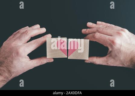 hands connecting or disconnecting woodenblocks with red heart, love or broken heart concept Stock Photo