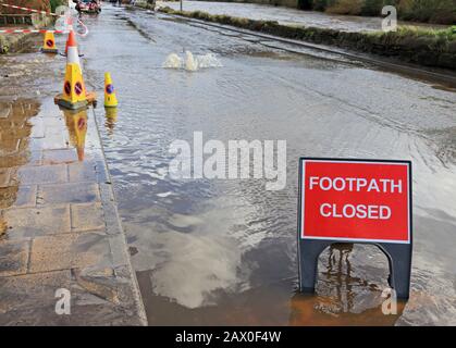 Water bubbles up from drain cover after heavy rainfall Stock Photo