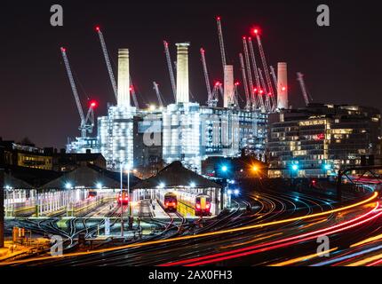 Trains going to and from Victoria Station passing Battersea Power Station at night Stock Photo