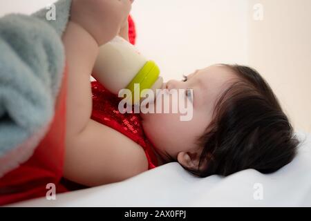 Closeup to Asian Thai Sweet Baby Girl Sucking Milk from Bottle Stock Photo