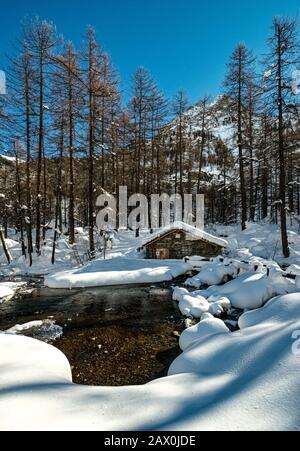 Italy Valle D' Aosta - Val di Rhemes - The ancient Pellaud mill and part of Lake Pellaud are set in a beautiful forest in the valley floor. Stock Photo