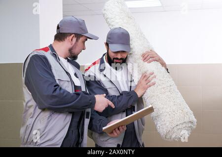 Happy male carrying a carpet in new home Stock Photo