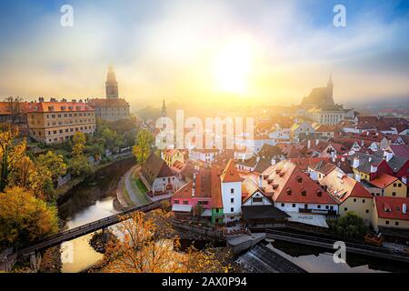 Classic panoramic view of historic city of Cesky Krumlov with famous Castle in beautiful golden morning light at sunrise with mystic fog in fall Stock Photo