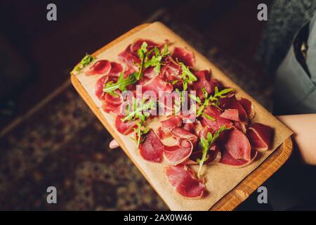 Antipasto set platter on wooden plate close up. Cold smoked meat plate with sausage,sliced ham,prosciutto, bacon, olives and basil. Appetizer on woode Stock Photo