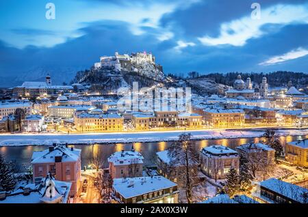 Classic aerial view of historic city of Salzburg with famous Festung Hohensalzburg and Salzach river illuminated in winter, Salzburger Land, Austria Stock Photo