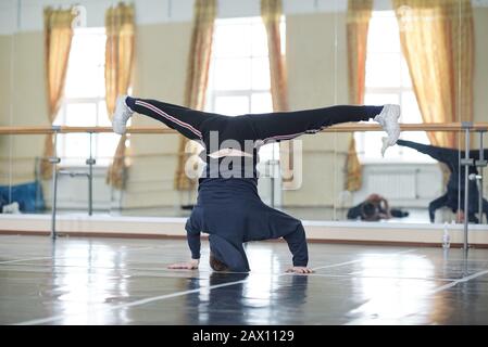 Horizontal shot of unrecognizable young man doing headstand in dance rehearsal studio room Stock Photo