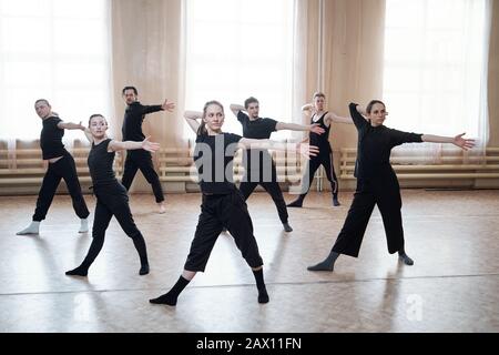 Horizontal shot of professional young dancers wearing black outfits reahearsing their new dance in studio Stock Photo