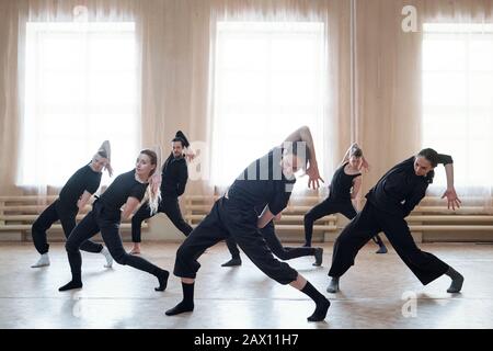 Team of contemporary dancers working on new dance moves together in their rehearsal studio, horizontal shot Stock Photo