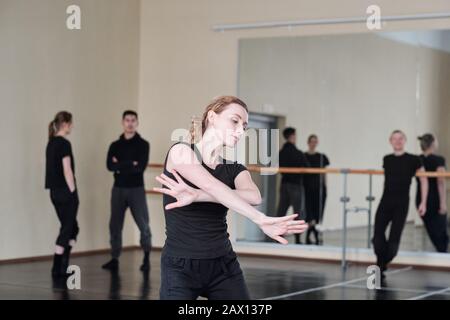 Horizontal medium portrait of beautiful young woman wearing black clothes dancing in rehearsal studio Stock Photo