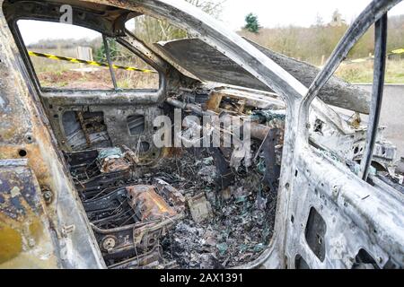 Close up of isolated, burnt out Renault Scenic car (driver's seat area) abandoned on UK wasteland. Vandalism and motor crime in the UK. Police aware. Stock Photo