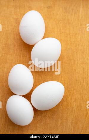 five white eggs lie on a wooden board Stock Photo