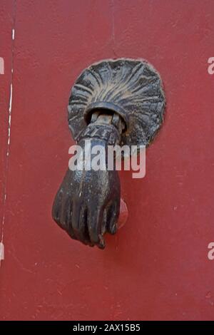 An ornate antique hand shaped door knocker on a door in Montpellier, France Stock Photo