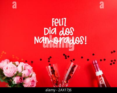 Feliz Dia dos Namorados (text in Portuguese: Happy Valentine's Day) and red  tulips blooming with green stalk against a light blue sky background. Conc  Stock Photo - Alamy