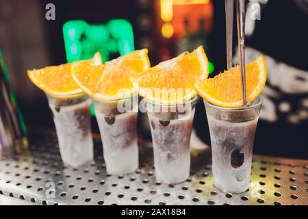 Bartender pouring strong alcoholic drink into small glasses on bar, shots Stock Photo
