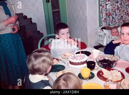 Six year old Ian Pilbeam at his birthday party with sister in cot and mother having lit the candles, February 1960 Stock Photo