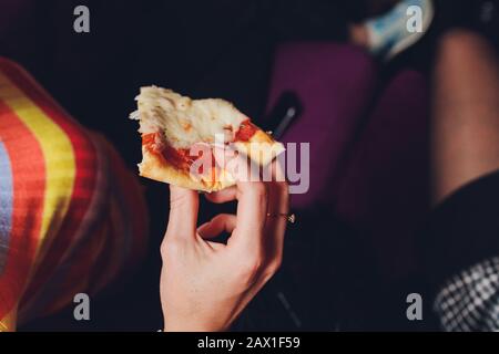 Close up female hand holding, taking slice, piece of pizza from box, friends sitting together in cafe, spending free time, eating Italian fast food, e Stock Photo