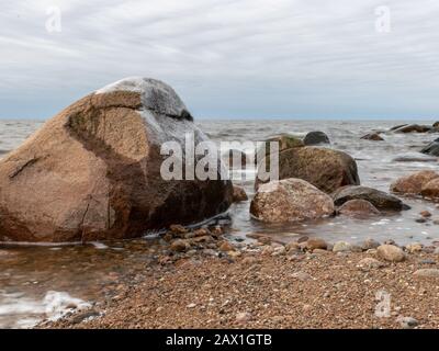 landscape with rocky beach in the evening, sun hiding behind clouds, beautiful sky Stock Photo