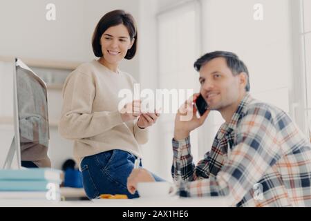 Young married couple study contract for new house, check documents for buying property, man discusses something with partner via cellphone, happy woma Stock Photo