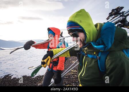 Woman and man laughing while walking with skis in Iceland