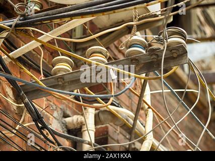 Obsolete electrical network, old wires fixed to brick building facade. Shanghai, China. Stock Photo