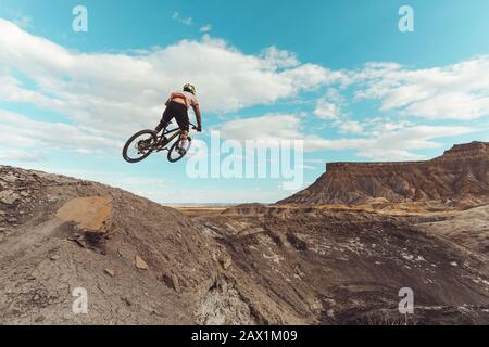 Male jumping with mountain bike in front of dramatic mountains Stock Photo