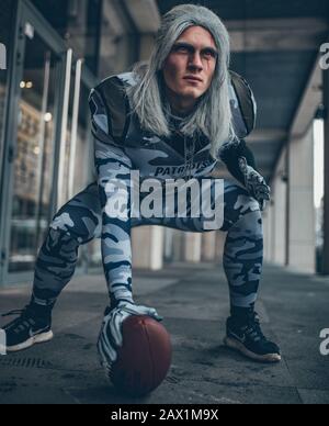 Man dressed as football team player in American football with ball in his hand. Stock Photo