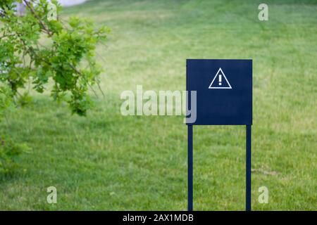 Closeup black metal sign at green grass background, nameplate with a space for your text, copyspace, empty space for inscription Stock Photo
