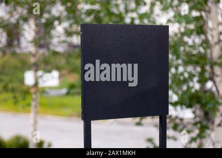 Closeup black metal sign at green grass background, nameplate with a space for your text, copyspace, empty space for inscription Stock Photo