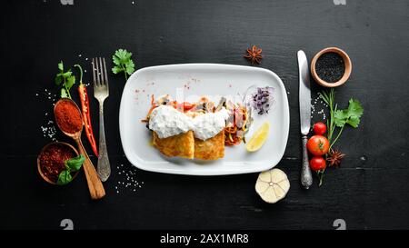 Fried fish fillet with vegetables in creamy sauce. In the plate. On a wooden background. Top view. Free space for your text. Stock Photo