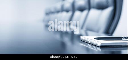 Closeup of notepad kept on table in empty conference room Stock Photo