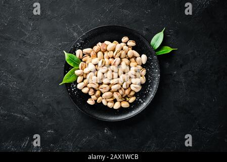 Salt pistachios in a bowl on a black background. Top view. Free space for your text. Stock Photo