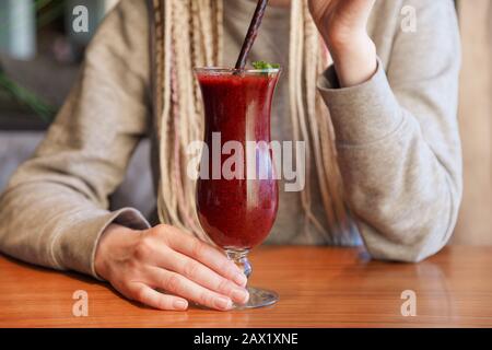 Glass of smoothie cocktail made of blackberry, blueberry, strawberry and vanilla in woman's hands Stock Photo