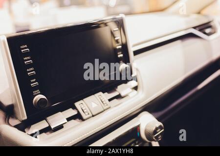 Control panel in the car near a blurred steering wheel. Black leather car interior with modern technologies on the dashboard,air conditioning,built-in Stock Photo